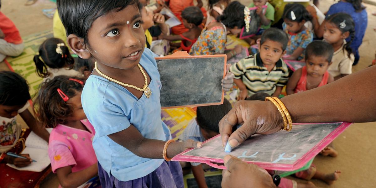 A child of Indian migrant labourers interacts with a teacher at a 'Tent School' run by a non-governmental organisation (NGO) 'Concern for Working Children (CWC)' in Bangalore on September 7, 2011 on the eve of 'International Literacy Day'. The provisional 2011 census figures show that the southwestern Indian state of Karnataka?s literacy rate has improved from 66 per cent to 75.60, with more girls than boys enrolling in educational schemes in the past decade. AFP PHOTO/ Manjunath Kiran (Photo credit should read Manjunath Kiran/AFP/Getty Images)